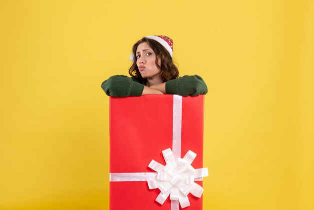 圣诞节正面图年轻女性藏在黄色的礼物盒里成人女人微笑