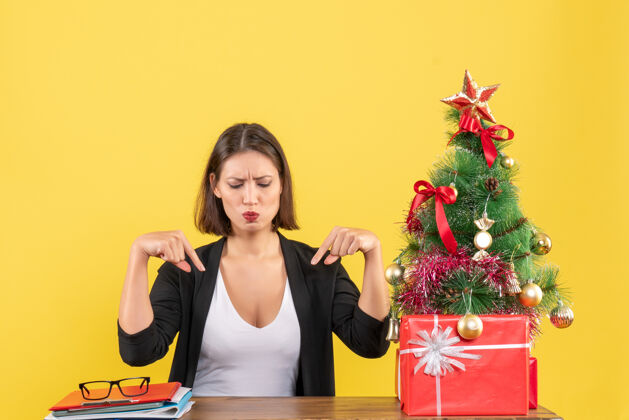 黄色在黄色的办公室里 一位穿着西装的年轻女士指着装饰好的圣诞树 惊讶地说肖像成人圣诞