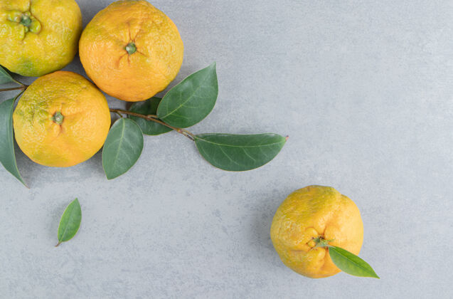 配料一捆美味的橘子和叶子放在大理石上风味叶多汁