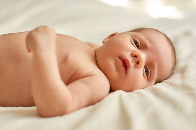 新生儿可爱的新生婴儿躺在床上的白色毯子上 研究着外面的事物 可爱可爱的婴儿 美丽的孩子看着远处华丽睡眠无辜