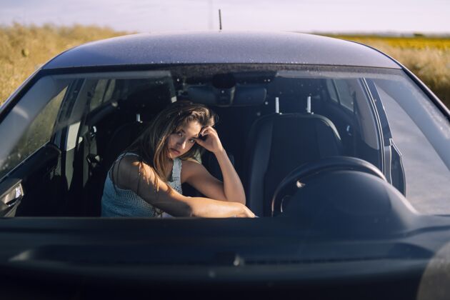 汽车一个美丽的年轻白人女性在一个领域的汽车前排座位摆姿势的水平镜头白种人女人车