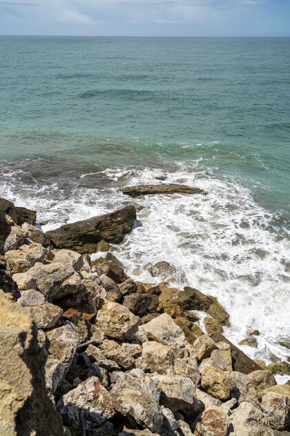 阳光白天阳光下被岩石包围的大海的垂直镜头阳光石头海洋