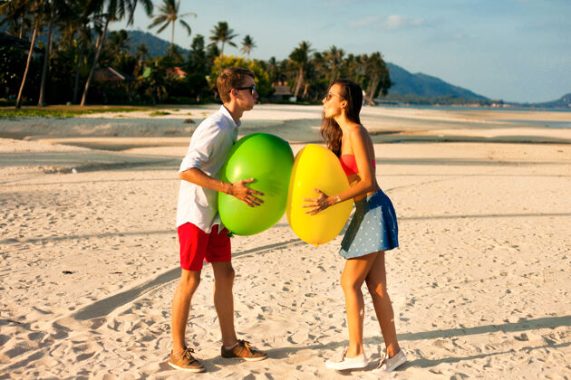 男孩两个快乐的年轻人在沙滩上约会和玩耍的可爱肖像时尚女人浪漫