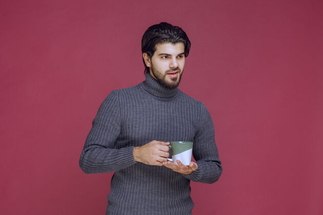 模特一个穿着灰色毛衣的男人手里拿着一个咖啡杯人休闲员工