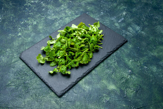 营养绿色-黑色混合色背景上的木质砧板上的胡荽捆的正面视图 有自由空间食物切蔬菜