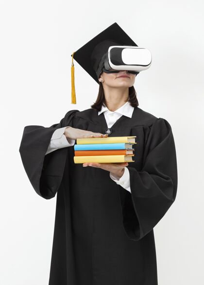 毕业穿着毕业礼服戴毕业帽戴着虚拟现实耳机的女人虚拟现实眼镜虚拟现实模拟器技术