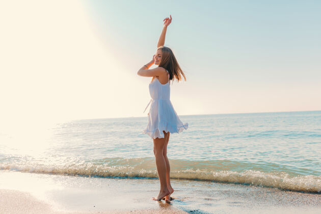 自然年轻迷人的快乐女子在海边跳舞转身阳光明媚的夏日时尚风格白色连衣裙活跃夜晚束腰外衣