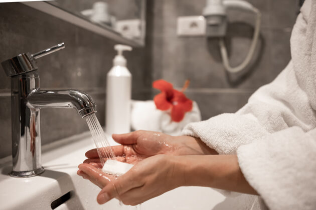 肥皂一个穿着晨衣的女人在自来水下用肥皂洗手水龙头浴室清洁