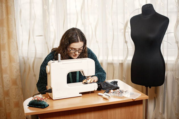 人打字机里的布料女人熟练地用缝纫机工作戴眼镜的女人缝纫专业裁缝