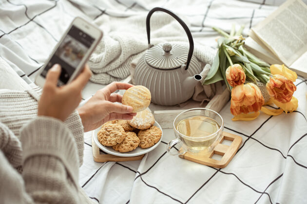 舒适一个女孩用手机拍下了春天的作文 床上摆着茶 饼干和郁金香床茶早晨