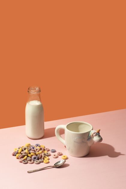 牛奶牛奶瓶 五颜六色的谷类食品和一个粉红色表面有独角兽的杯子鸡尾酒杯子健康