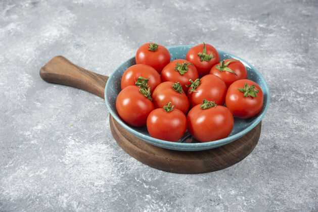 美味蓝色的碗里装满了红色的新鲜西红柿放在大理石上食物木头西红柿