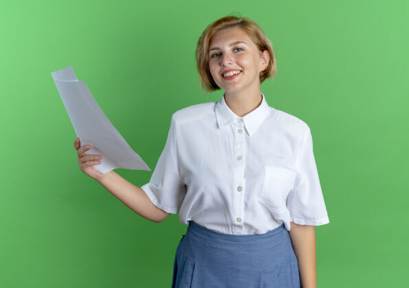 被单年轻的微笑着的金发俄罗斯女孩拿着纸页孤立的绿色背景与复制空间年轻金发微笑