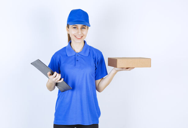 人穿着蓝色制服的女孩手里拿着一个纸板外卖盒和一份顾客名单休闲成人年轻人