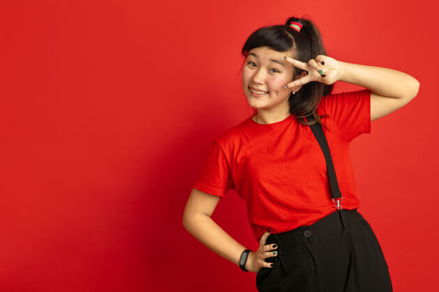 亚洲人亚洲青少年的肖像画独立于红色工作室背景美丽的深褐色女性模特 留着休闲的长发人类情感的概念 面部表情 销售 广告摆可爱的姿势行政人员商人公司