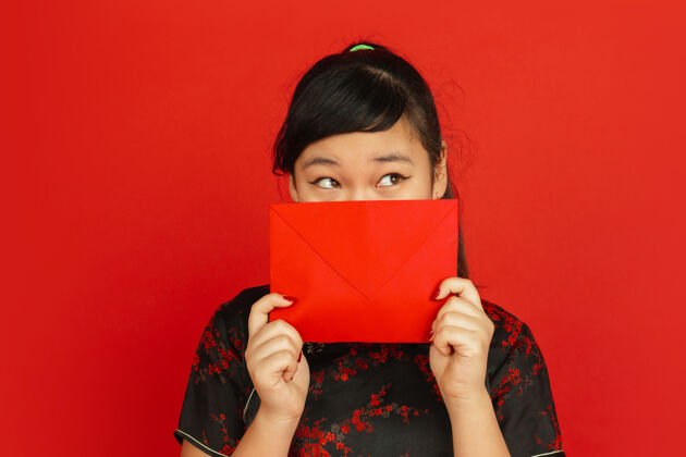 旗袍2020年中国新年红色背景上孤立的亚洲少女肖像穿着传统服装的女模特看起来很梦幻 展示着红包庆祝 节日 情感服装旗袍青少年