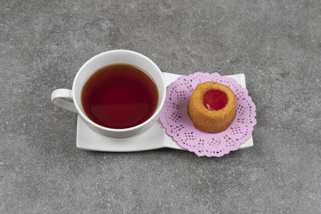 浆果在大理石表面涂上果冻和茶的小蛋糕茶杯子水果