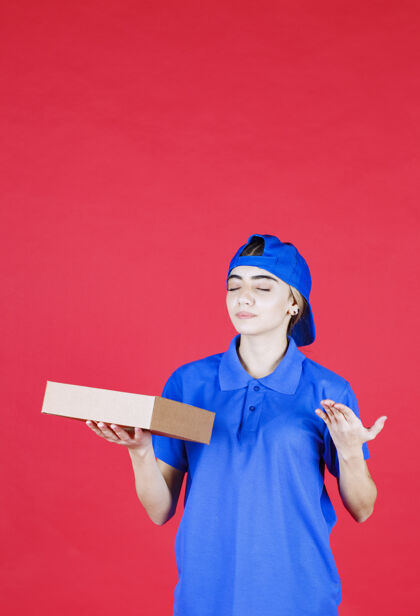 人穿着蓝色制服的女信使手里拿着一个纸板箱人员工食物
