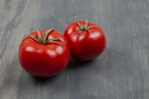生的两个新鲜的生西红柿和叶子放在木桌上成熟的有机番茄