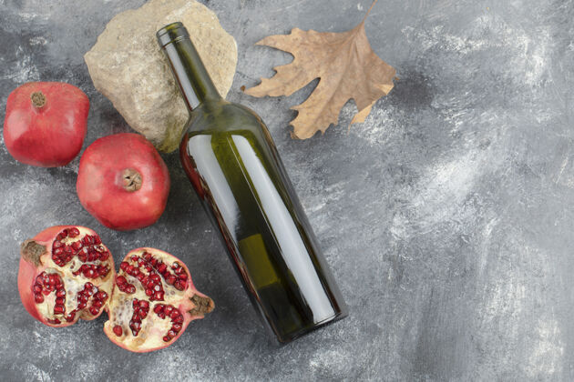 酒成熟的石榴水果和一瓶葡萄酒在大理石背景上石榴酒精美味