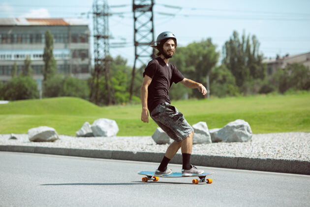 运动员在阳光明媚的日子里 在城市街道上玩滑板的人穿着装备的年轻人在沥青路面上骑行和玩长板休闲活动 运动 极限 爱好和运动的概念男孩人滑板