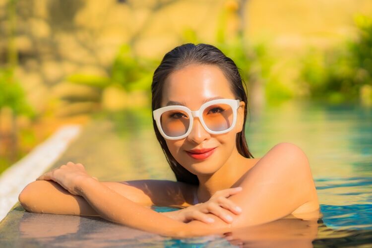 热带美丽的亚洲年轻女子在游泳池里放松的画像健康女性人