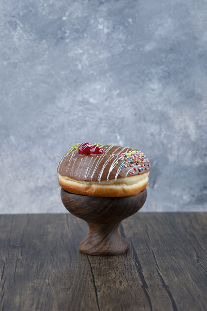 甜甜圈木碗美味的甜甜圈巧克力糖霜和洒在木桌上霜釉巧克力
