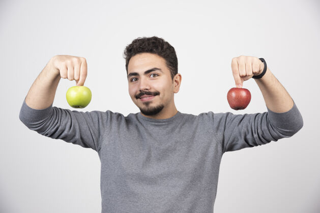 模型一个年轻人拿着两个苹果站在灰色的树上举行苹果休闲