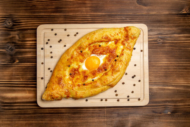 鸡蛋顶视图新鲜烤面包配煮熟的鸡蛋放在棕色木制书桌上面团面包早餐鸡蛋食品膳食面包奶酪