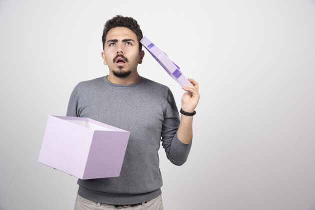 人类一个体贴的男人 在白墙上放着一个打开的紫色盒子模特礼物男人