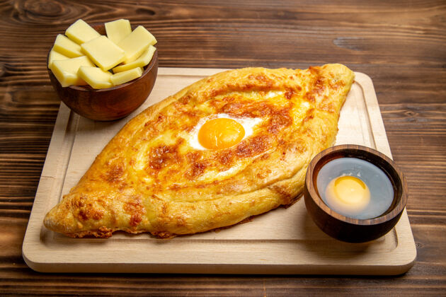 桌子正面图棕色木制书桌上的新鲜烤面包和熟鸡蛋面团餐包早餐鸡蛋食品鸡蛋早餐晚餐
