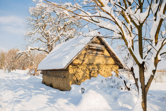 明亮冬天的阳光下 一个被雪覆盖的田野里的小屋田野雪乡村