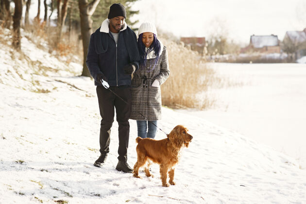 约会人们在外面散步冬天非洲夫妇带着狗女人一起情侣