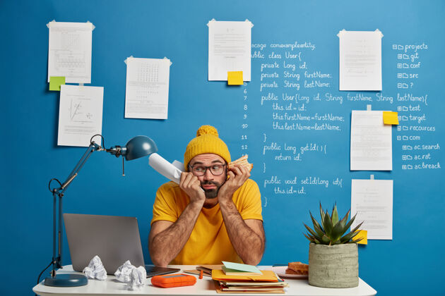 网站悲伤的男生准备写考试 在同事的空间摆姿势 拿着纸和汉堡 穿着黄色的衣服零食工作办公桌