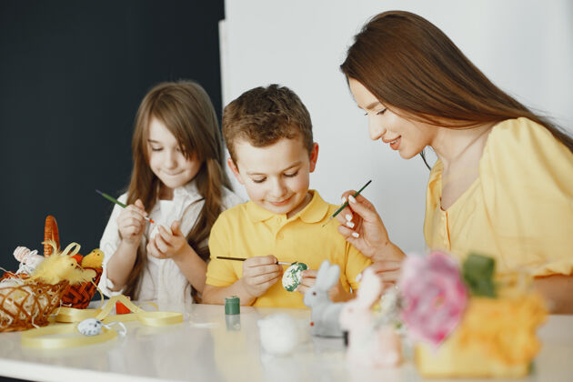 童年孩子们画鸡蛋妈妈教孩子们坐在一张白色的桌子旁符号室内传统