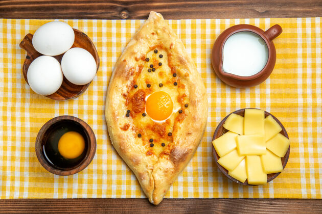 切片顶视图生鸡蛋与切片奶酪鸡蛋面包和牛奶在木制表面产品鸡蛋面团餐食品生早餐盘子一餐