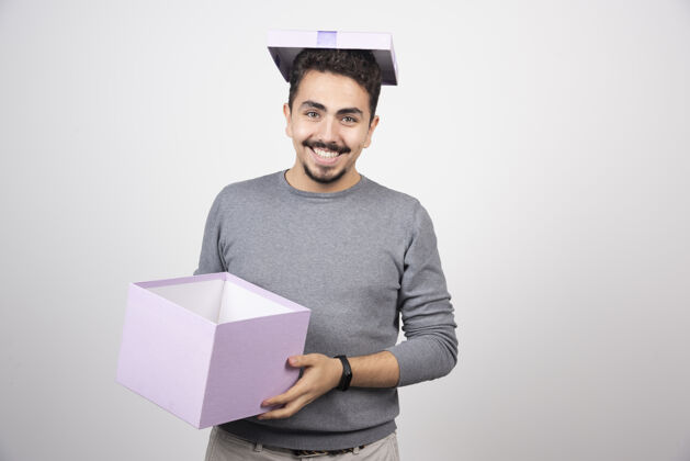 礼物微笑的男人手里拿着一个紫色的盒子人类男孩模特