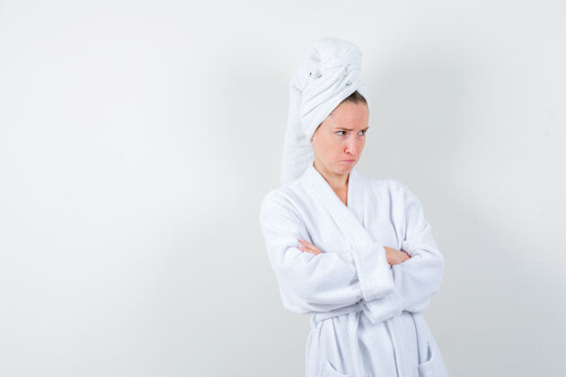 成人身穿白色浴衣 交叉着胳膊站在毛巾上 神情阴郁的年轻女子 正面照交叉毛巾微笑