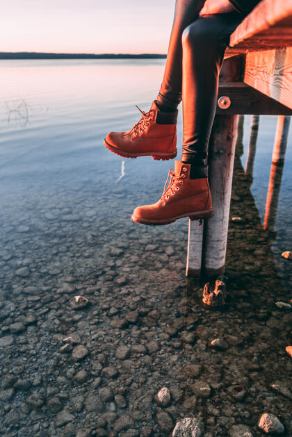 冷在湖边木制人行道上的女人腿湖石头