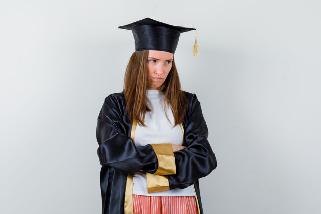 成人毕业的女人穿着休闲服 穿着制服 双臂交叉站着 神情阴郁 俯瞰前方手臂立场教育