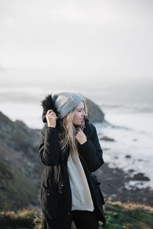 站年轻的金发女郎戴着帽子在有风的海滩上玩得很开心季节风沙