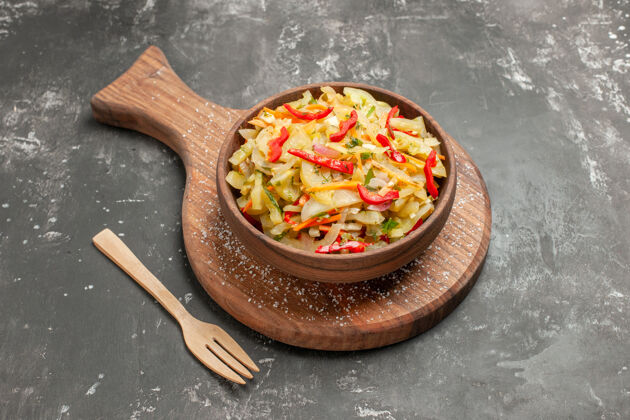 胡椒侧面特写查看色拉蔬菜色拉在棕色碗上的厨房木板木叉上肉板食物