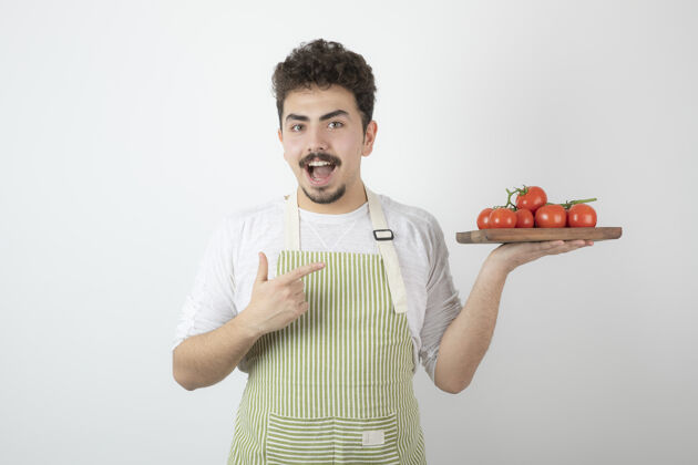 人兴奋的年轻人拿着一堆新鲜的西红柿 用手指着它西红柿人蔬菜