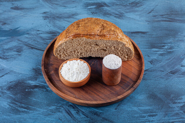 黑麦在蓝色的表面上放着一碗面粉的黑麦面包面包面粉小吃