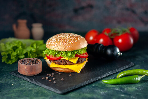 深色前视图美味的肉汉堡包与红色西红柿在黑暗的背景快餐食物番茄