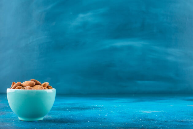 美味在蓝色表面的碗里放着没有壳的杏仁健康自然碗