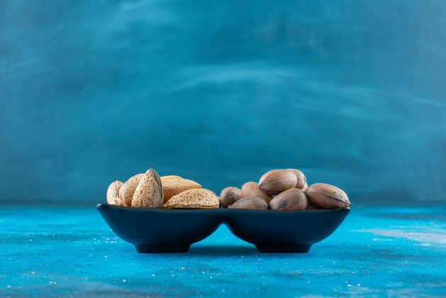杏仁山核桃和杏仁放在蓝色的碗里风味壳自然