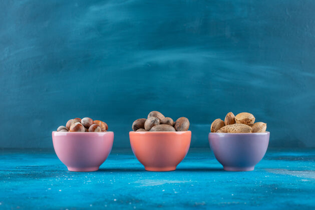 美味蓝色表面的碗里有各种各样的坚果健康坚果可口
