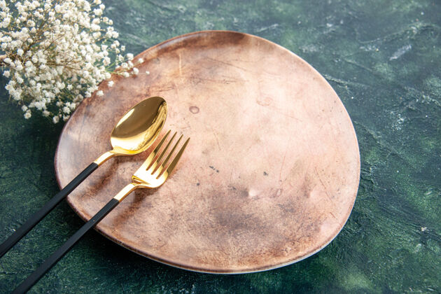 食物前视图棕色板与金色勺子和叉子在黑暗的背景深色的正餐晚餐