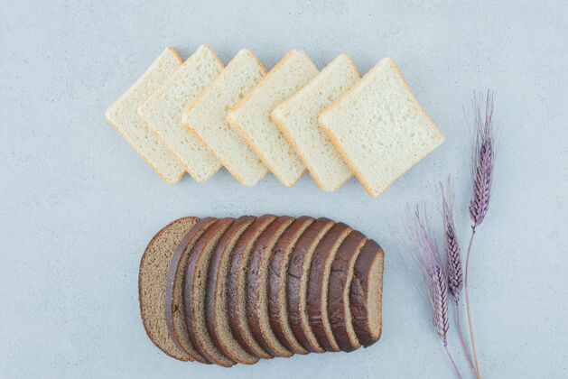 黑麦烤面包和黑面包片放在石头表面和小麦美味不同顶视图